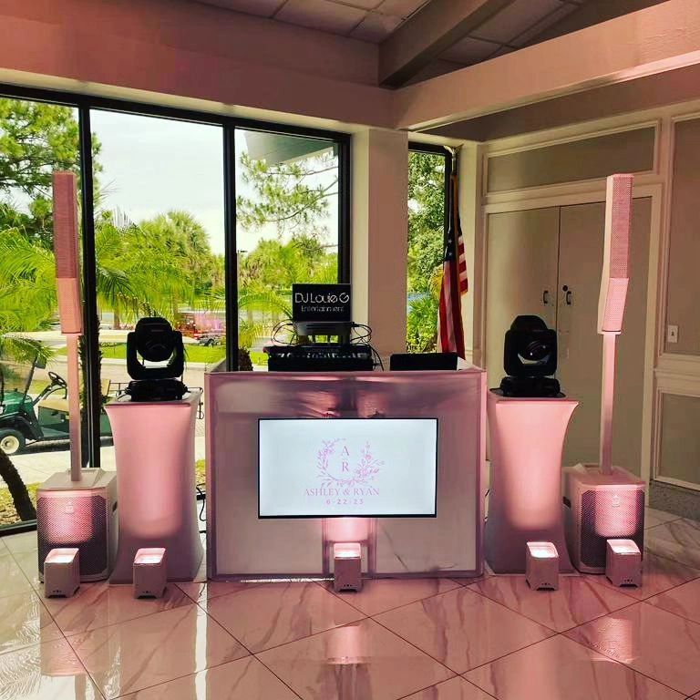 Elegant DJ booth setup with speakers and lighting in a bright room.
